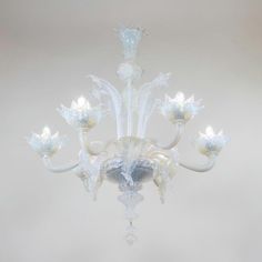 a white chandelier with frosted glass flowers hanging from it's center