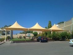 a car is parked in the parking lot under two large umbrellas over it's roof