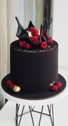 a black cake with red raspberries on top