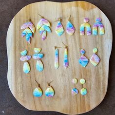 a wooden tray with different colored earrings on it