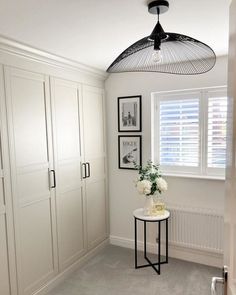 a room with white cabinets and pictures hanging on the wall next to a table in front of a window