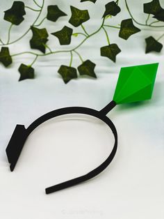 a green piece of paper sitting on top of a white table next to some leaves