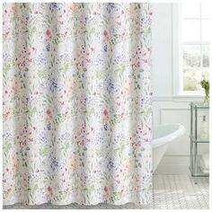 a shower curtain with flowers on it and a white bath tub in the back ground