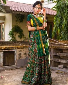 a woman in a green and yellow sari with her hand on her hip, posing for