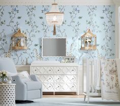 a baby's room with blue and white wallpaper, crib, chair, dresser and mirror