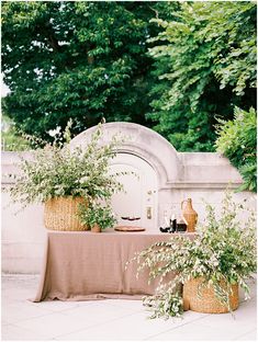 an outdoor table with plants and vases on it