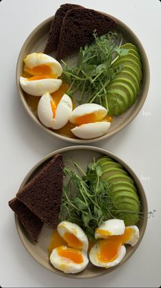 two plates filled with food on top of a white tablecloth covered countertop, one has an egg and the other has avocado