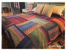 a bed covered in multicolored blankets and pillows