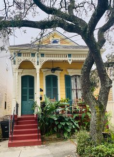 a yellow house with green doors and red steps