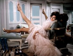 a black and white photo of a woman laying on a chair with her legs in the air