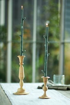 two candles are sitting on a table next to each other in front of a window