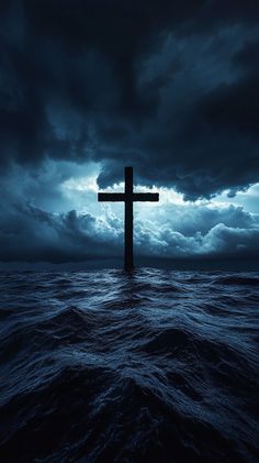 a cross in the middle of water under a cloudy sky with dark clouds above it