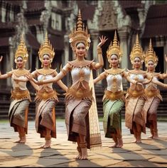 a group of women dressed in thai garb and headdresses dance together