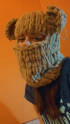 a woman wearing a knitted bear hat with chains around her neck and earrings