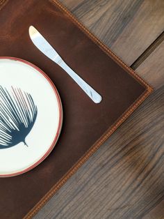 a plate with a fork and knife on it next to a brown leather napkin holder