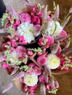 a bouquet of pink and white flowers sitting on top of a brown potted plant