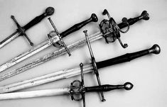 several different types of swords are arranged in a row on a white surface with black and white background