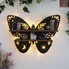 a butterfly shaped wall shelf with some rocks and plants on the shelves next to it