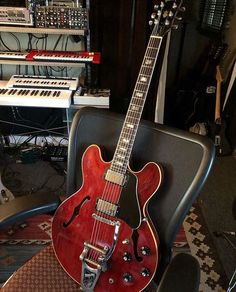 a red electric guitar sitting on top of a chair in front of a computer keyboard