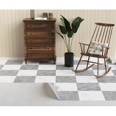 a rocking chair sitting on top of a checkered floor next to a potted plant