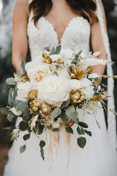 a bride holding a bouquet of white and gold flowers