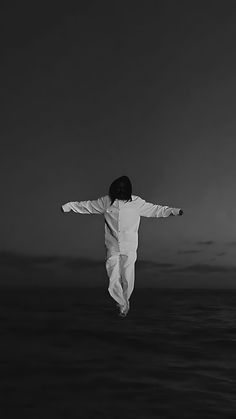 a man in white jumps into the air with his arms spread wide and hands outstretched