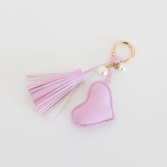 a pink heart shaped keychain with tassels and pearls on the end