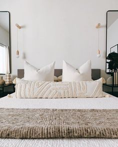 a bed with white pillows and two mirrors