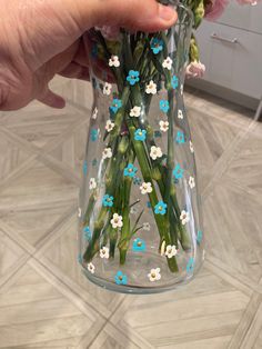 someone is holding a vase with flowers in it