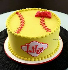 a birthday cake decorated with a softball and the word lilly on it's side