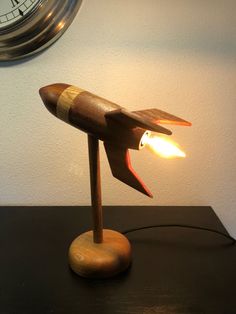 a wooden airplane lamp sitting on top of a table next to a wall mounted clock