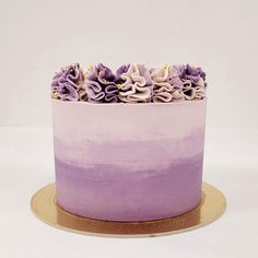 a purple and white ombreed cake with flowers on top sits on a gold plate