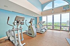 there are many treadmills in the gym with large windows looking out on the city