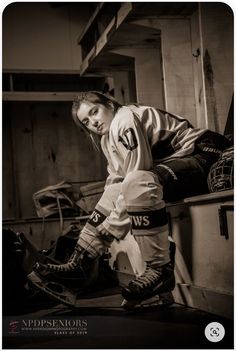 a woman sitting on top of a wooden bench wearing hockey gear and holding her leg up