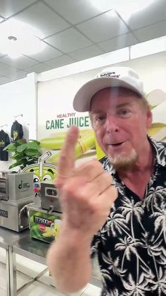 a man in a hat is making the peace sign with his hand while wearing a black and white shirt