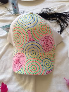 a colorful hat sitting on top of a bed next to hair dryer and other items