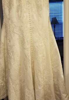 a white dress hanging on a rack in front of a window