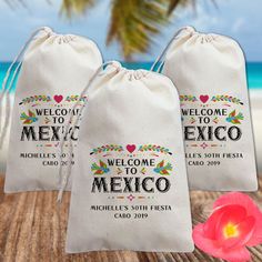 two bags with welcome to mexico on them and a pink flower in the foreground