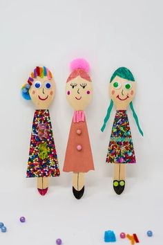 three wooden dolls are standing next to each other with sprinkles all over them