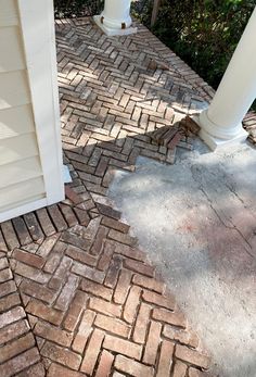 a white fire hydrant sitting on the side of a brick road next to a house