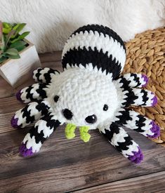 a crocheted black and white stuffed animal sitting on top of a wooden table