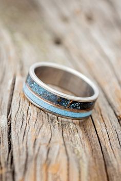 a close up of a wedding ring on a wooden surface with blue and white stripes