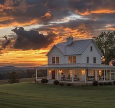 a large white house sitting on top of a lush green field under a cloudy sky