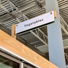 a sign hanging from the side of a building that says vegetables on it's front