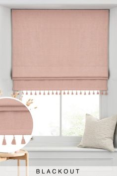 a pink roman blind with tassels on the top and bottom, in front of a window