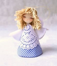 an angel doll with blonde hair wearing a blue and white checkered dress on a white background