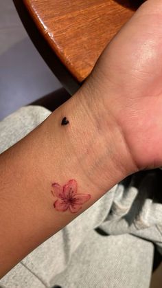 a person with a small flower tattoo on their wrist