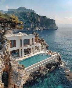 an aerial view of a house on the edge of a cliff overlooking the ocean and mountains