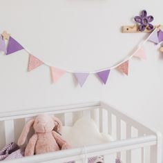 a baby crib with a stuffed animal in it and some decorations on the wall