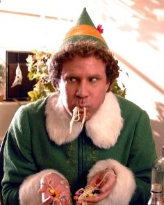 a man wearing a party hat and eating spaghetti with his hands in front of him